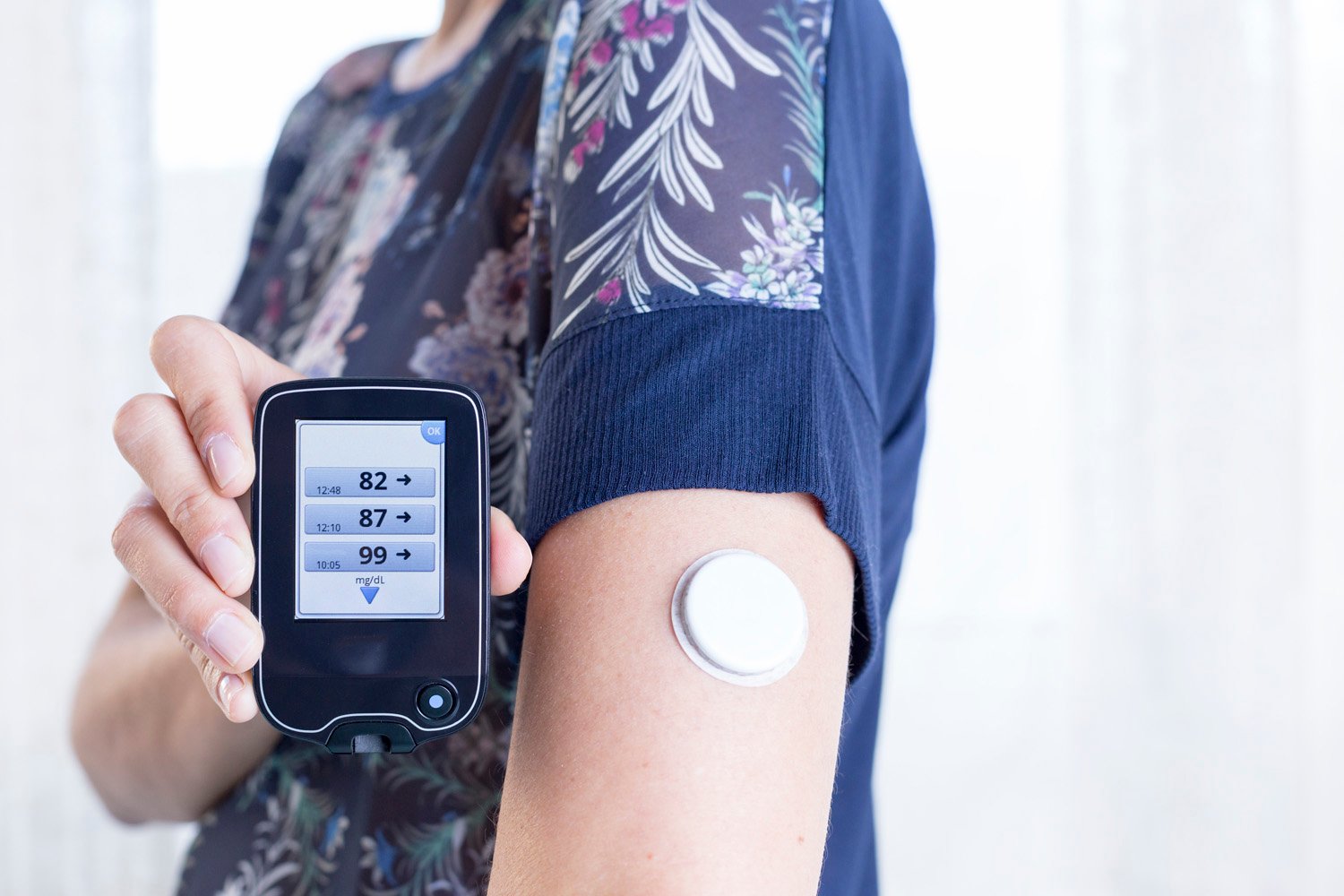 closeup of a hand of a young woman showing the reader after scanning the sensor of the glucose monitoring system - focus on the reader